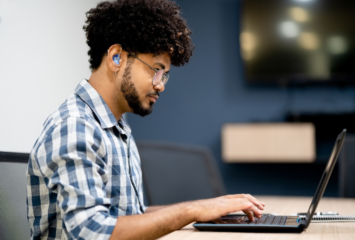 Man with hearing loss works on laptop